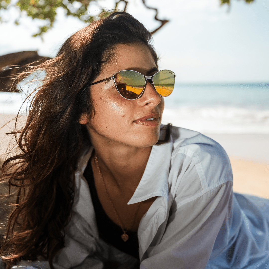 Woman wearing sunglasses with a beach in the background