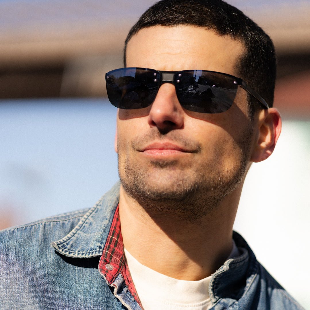 Close-up of a man wearing Lex sunglasses with a rimless design and dark lenses outdoors.